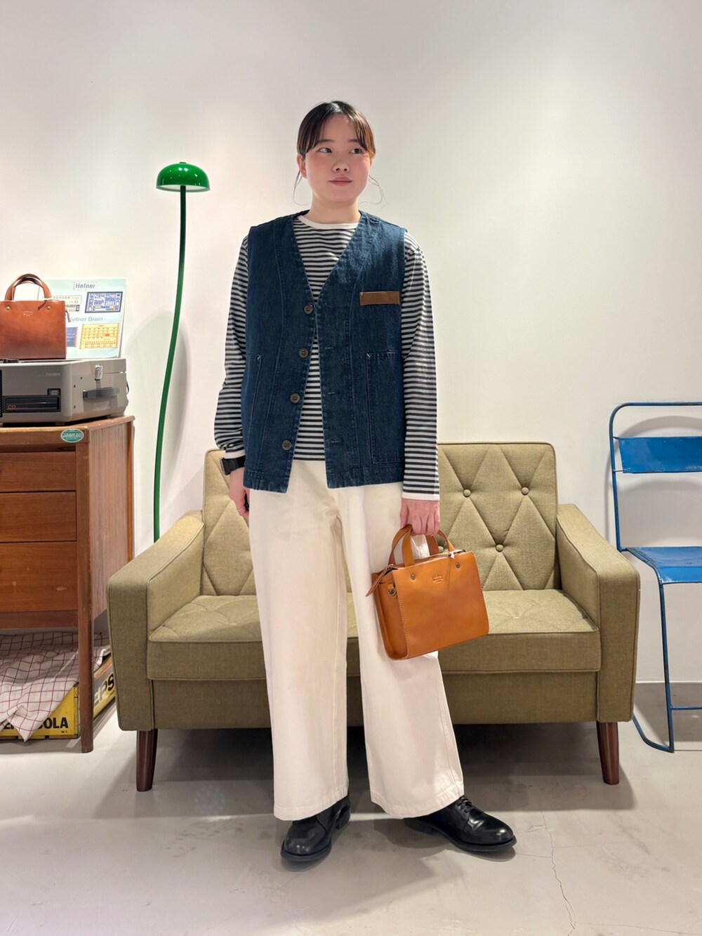 ブルー系のベスト、グリーン系のTシャツ/カットソー、ホワイト系のチノパンツを着用したレディースの冬コーディネートの4枚目の写真