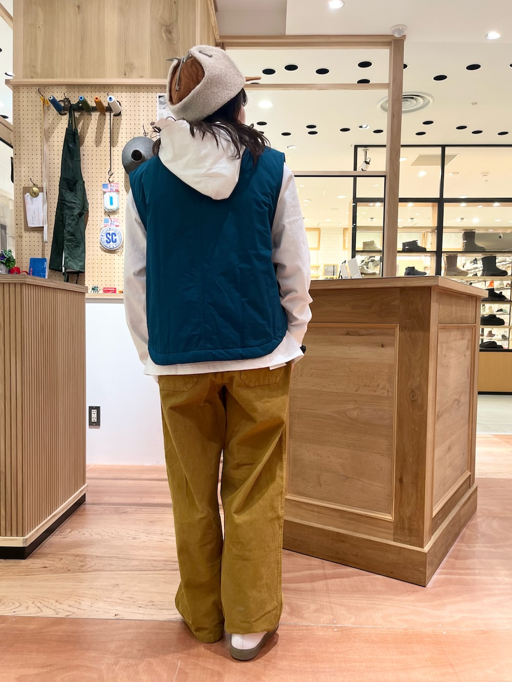 グリーン系のダウンベスト、イエロー系のその他パンツ、ホワイト系のTシャツ/カットソーを着用したレディースの秋コーディネートの3枚目の写真