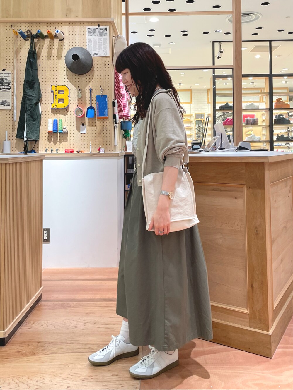 ホワイト系のTシャツ/カットソー、ベージュ系のカーディガン/ボレロ、ホワイト系のショルダーバッグを着用したレディースの春コーディネートの2枚目の写真