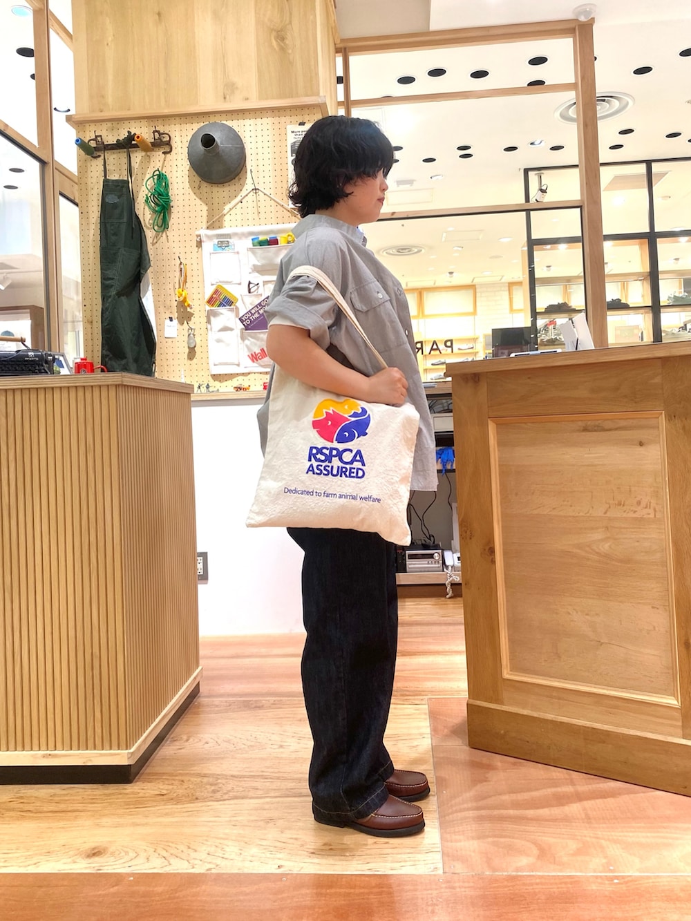 グレー系のシャツ/ブラウス、ブルー系のデニムパンツ、ブラウン系のモカシン/デッキシューズを着用したレディースの夏コーディネートの2枚目の写真