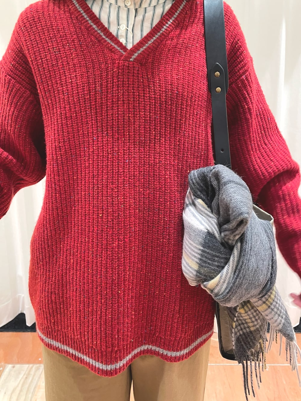 レッド系のニット/セーター、ベージュ系のチノパンツ、グリーン系のシャツ/ブラウスを着用したレディースの冬コーディネートの5枚目の写真