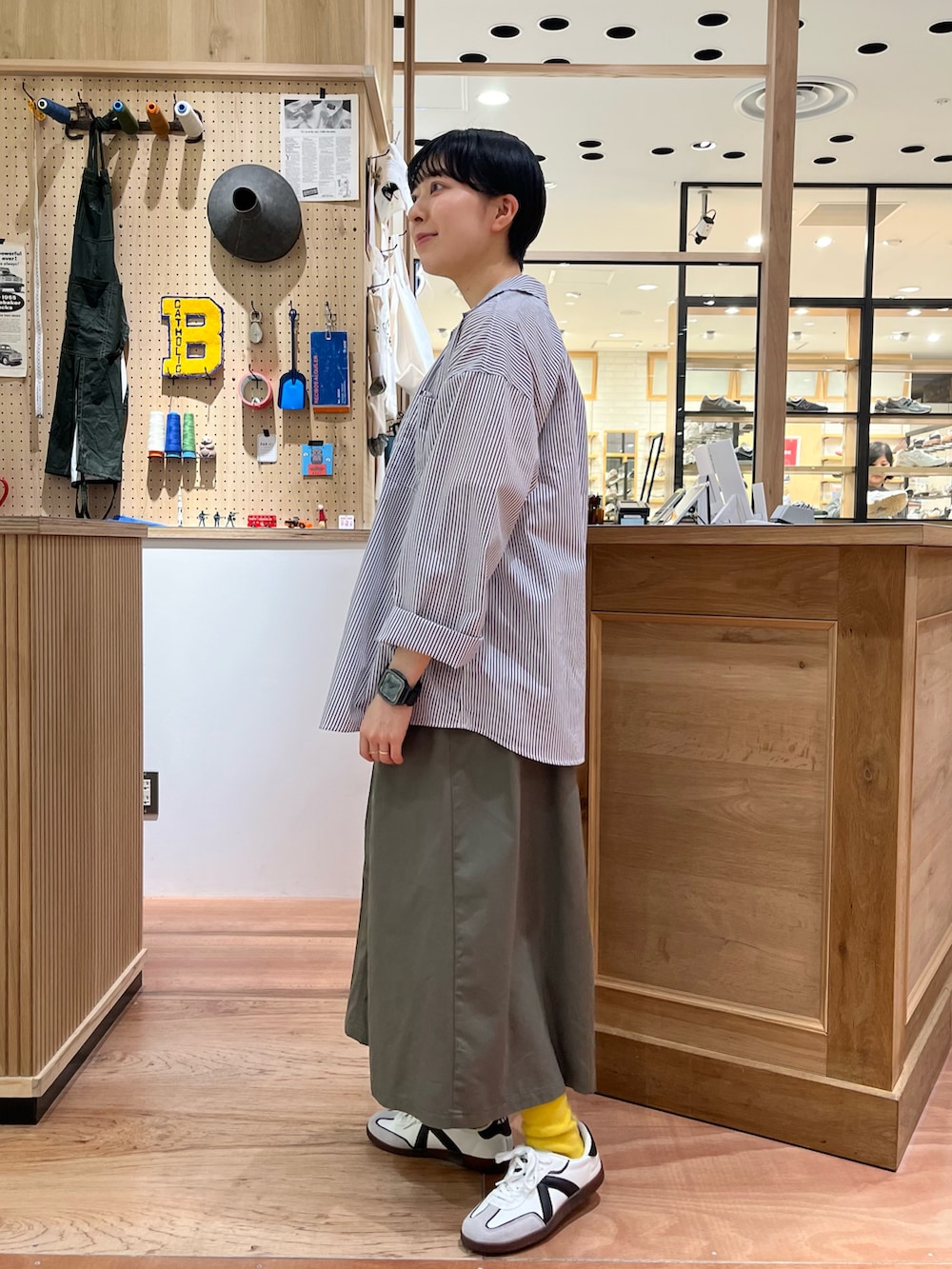 イエロー系のTシャツ/カットソー、ホワイト系のシャツ/ブラウス、グリーン系のスカートを着用したレディースの春コーディネートの2枚目の写真