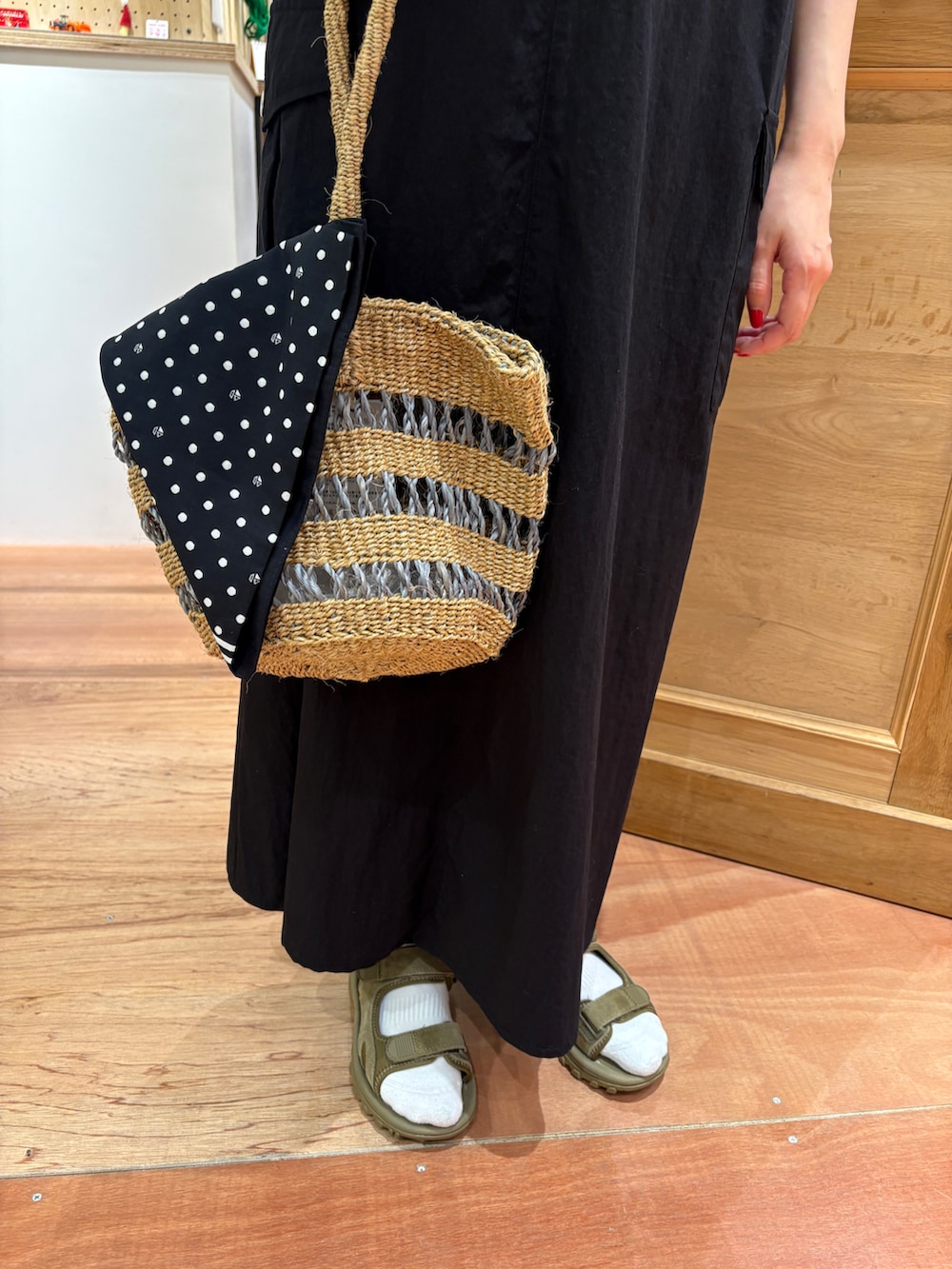 グリーン系のTシャツ/カットソー、ブラック系のジャンパースカート、グレー系のかごバッグを着用したレディースの春コーディネートの5枚目の写真