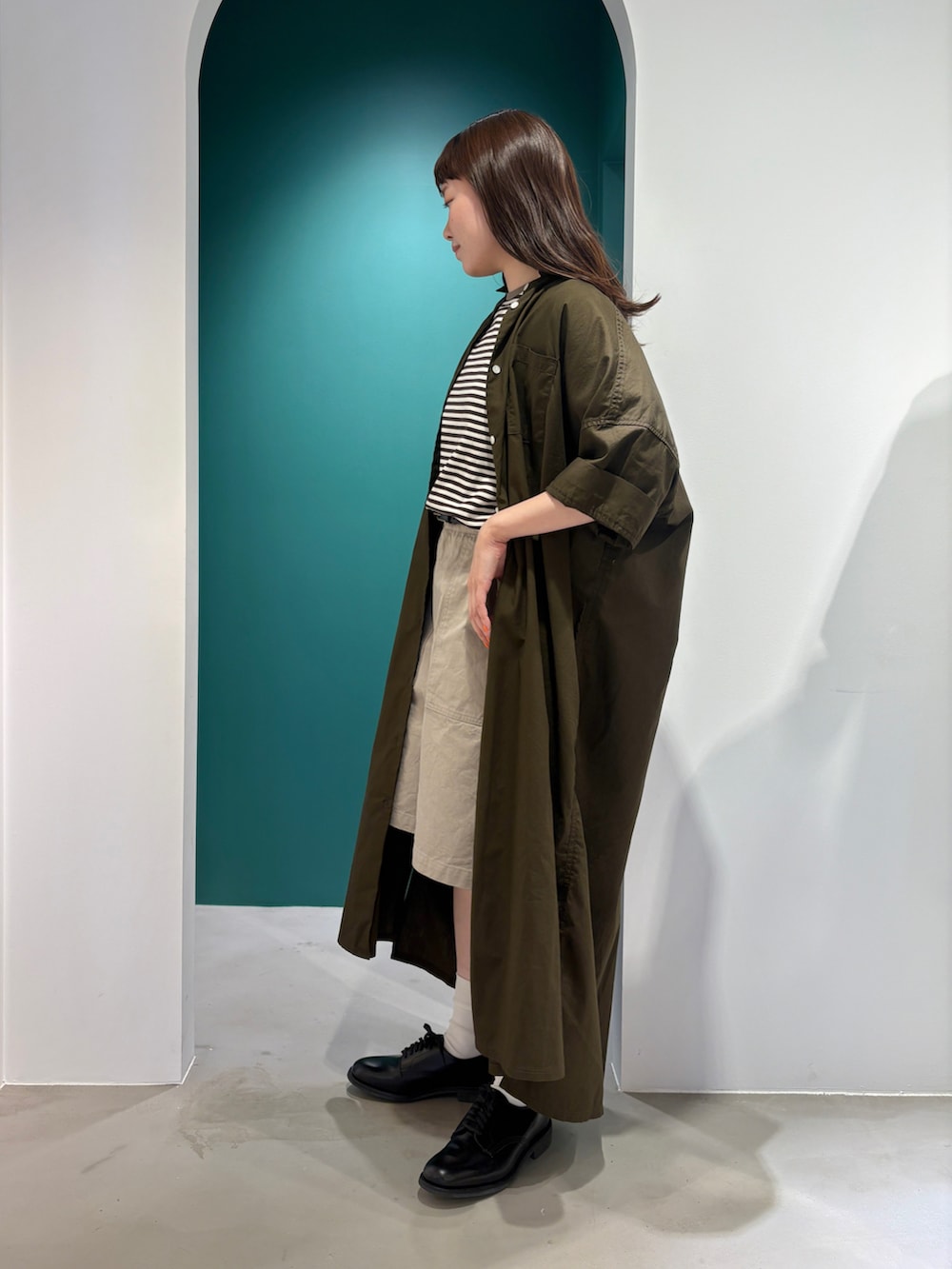 ブラウン系のTシャツ/カットソー、ブラウン系のシャツワンピース、ベージュ系のチノパンツを着用したレディースの夏コーディネートの2枚目の写真