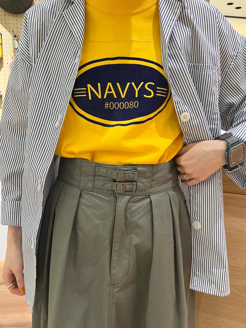 イエロー系のTシャツ/カットソー、ホワイト系のシャツ/ブラウス、グリーン系のスカートを着用したレディースの春コーディネートの4枚目の写真