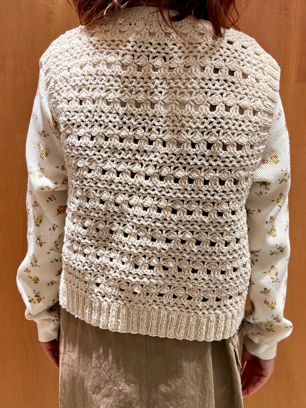 ホワイト系のベスト、オレンジ系のTシャツ/カットソー、ベージュ系のジャンパースカートを着用したレディースの冬コーディネートの5枚目の写真