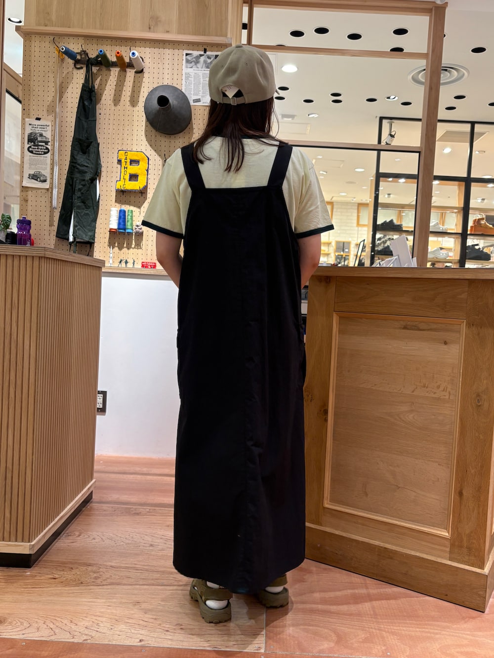 グリーン系のTシャツ/カットソー、ブラック系のジャンパースカート、グレー系のかごバッグを着用したレディースの春コーディネートの3枚目の写真