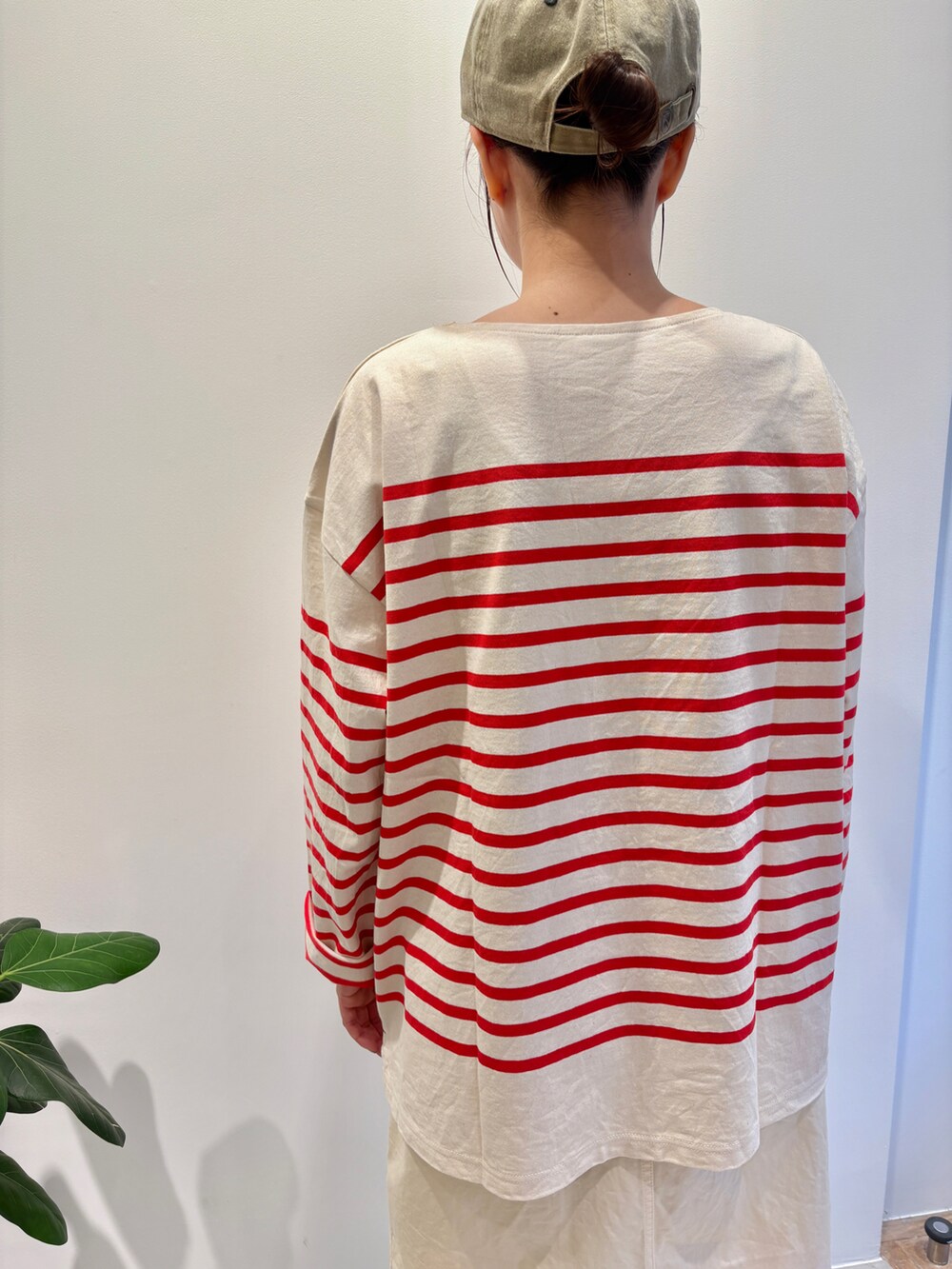 レッド系のTシャツ/カットソー、ホワイト系のスカート、グリーン系のキャップを着用したレディースの夏コーディネートの4枚目の写真