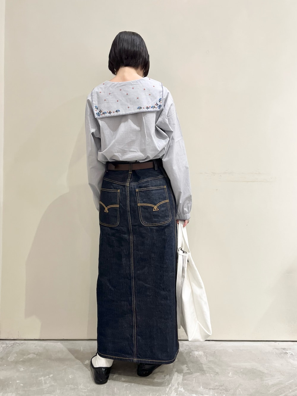 ブルー系のシャツ/ブラウス、ブルー系のデニムスカート、ホワイト系のトートバッグを着用したレディースの冬コーディネートの2枚目の写真