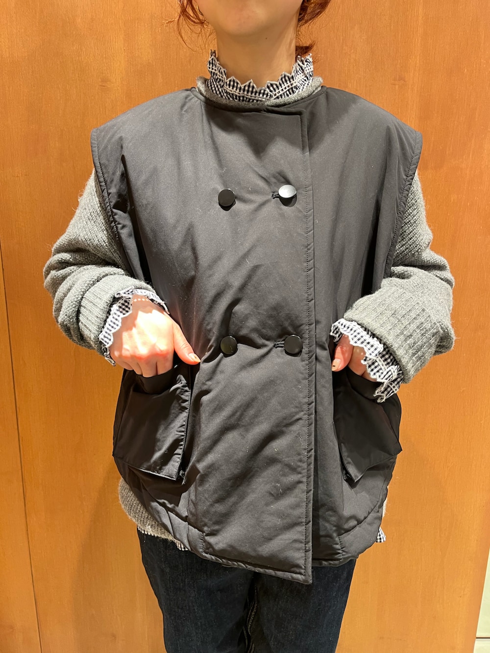 ブルー系のシャツ/ブラウス、グレー系のニット/セーター、ブラック系のダウンベストを着用したレディースの冬コーディネートの3枚目の写真