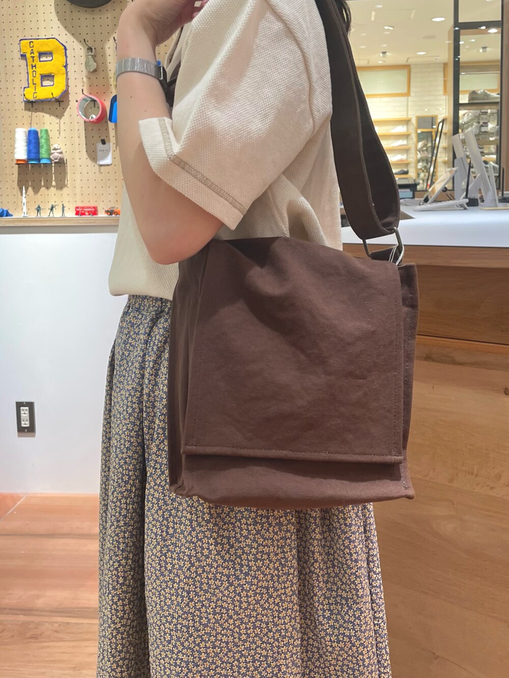 イエロー系のスカート、ブラウン系のショルダーバッグ、ホワイト系のポロシャツを着用したレディースの春コーディネートの5枚目の写真