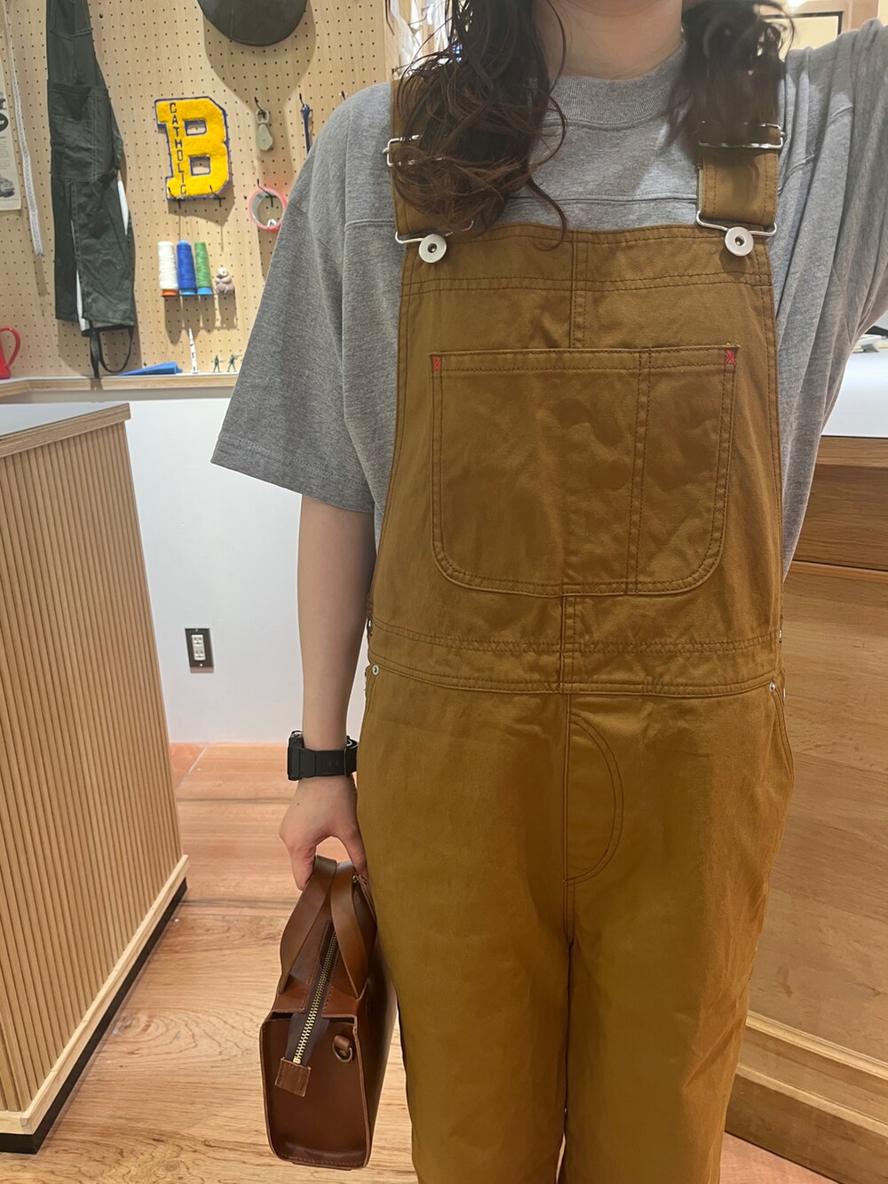 ブラウン系のサロペット/オーバーオール、ホワイト系のシャツ/ブラウス、グレー系のTシャツ/カットソーを着用したレディースの春コーディネートの5枚目の写真