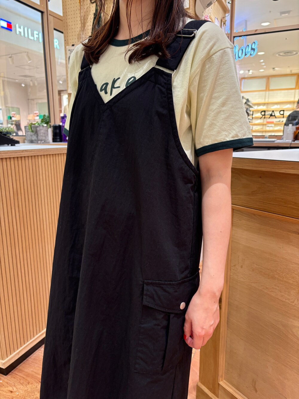 グリーン系のTシャツ/カットソー、ブラック系のジャンパースカート、グレー系のかごバッグを着用したレディースの春コーディネートの4枚目の写真