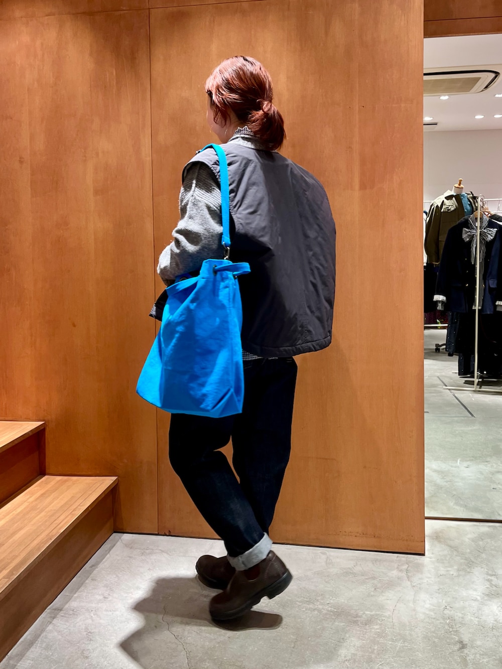 ブルー系のシャツ/ブラウス、グレー系のニット/セーター、ブラック系のダウンベストを着用したレディースの冬コーディネートの2枚目の写真