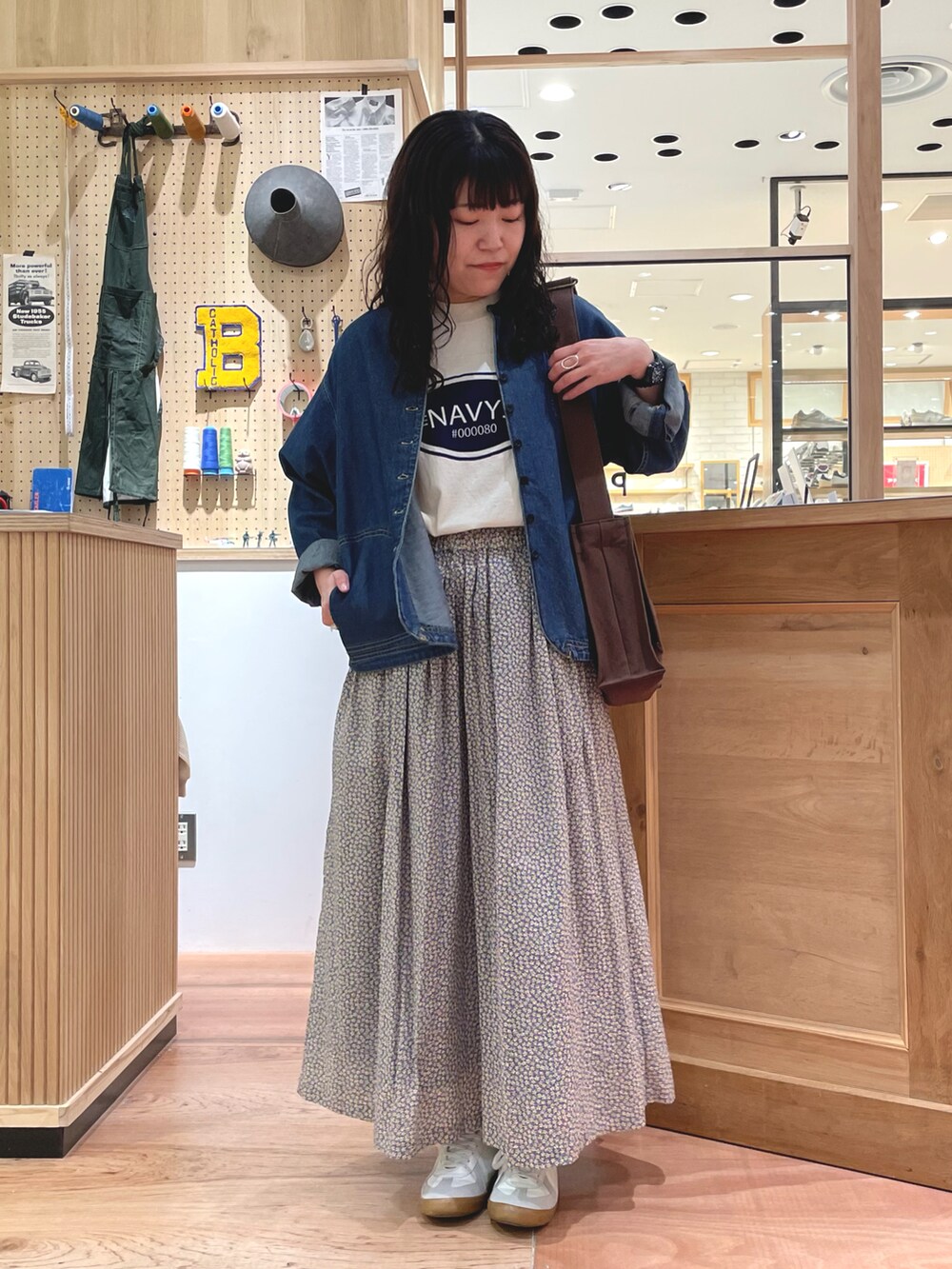 イエロー系のスカート、ブラウン系のショルダーバッグ、ブルー系のデニムジャケットを着用したレディースの春コーディネートの2枚目の写真