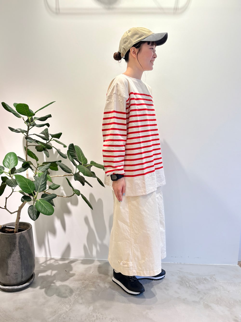 レッド系のTシャツ/カットソー、ホワイト系のスカート、グリーン系のキャップを着用したレディースの夏コーディネートの2枚目の写真