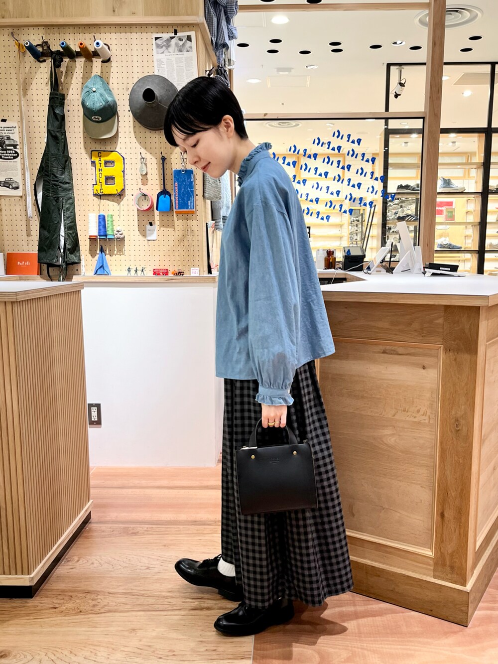 ブルー系のシャツ/ブラウス、グレー系のスカート、ブラック系のショルダーバッグを着用したレディースの秋コーディネートの2枚目の写真