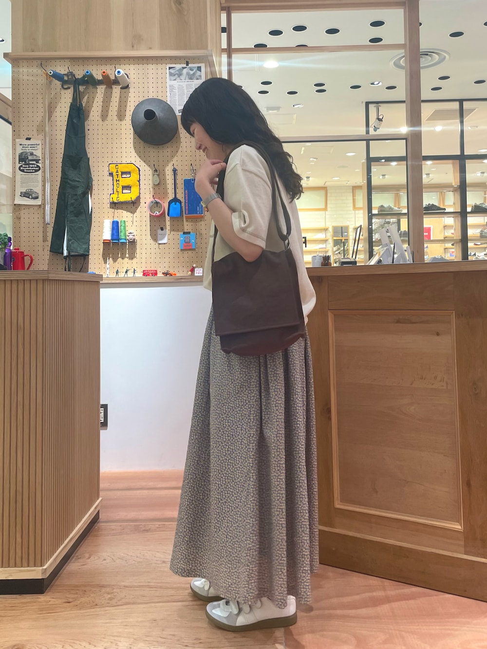 イエロー系のスカート、ブラウン系のショルダーバッグ、ホワイト系のポロシャツを着用したレディースの春コーディネートの3枚目の写真