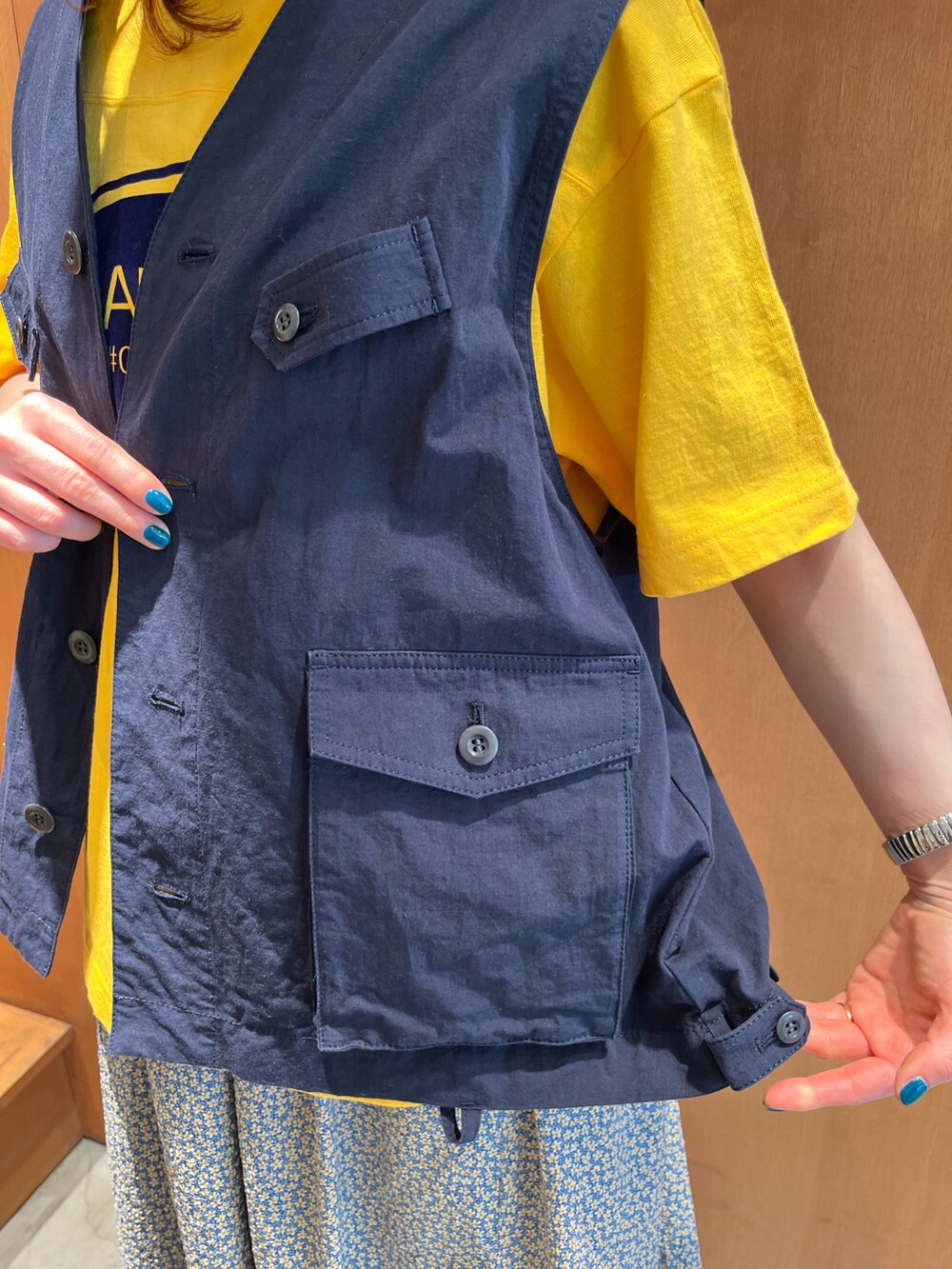 イエロー系のTシャツ/カットソー、ブルー系のベスト、イエロー系のスカートを着用したレディースの春コーディネートの5枚目の写真