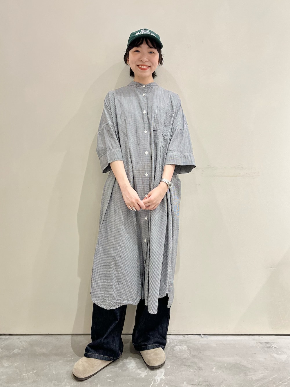 ブラック系のシャツワンピース、ブルー系のデニムパンツを着用したレディースの夏コーディネートの2枚目の写真