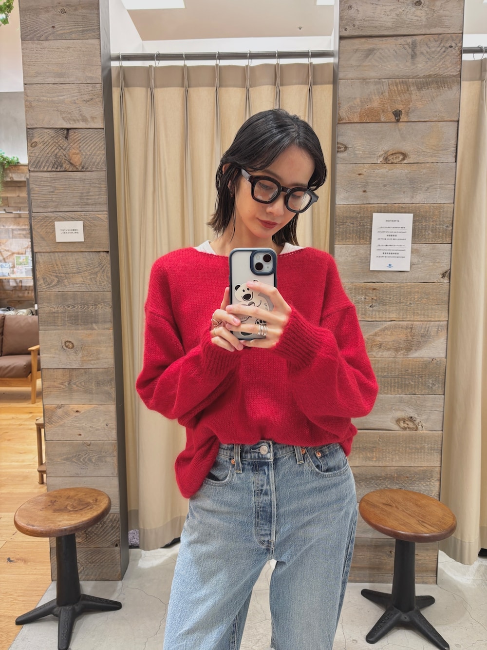 レッド系のニット/セーター、ブルー系のデニムパンツ、ブラック系のシューズを着用したレディースの秋コーディネートの2枚目の写真