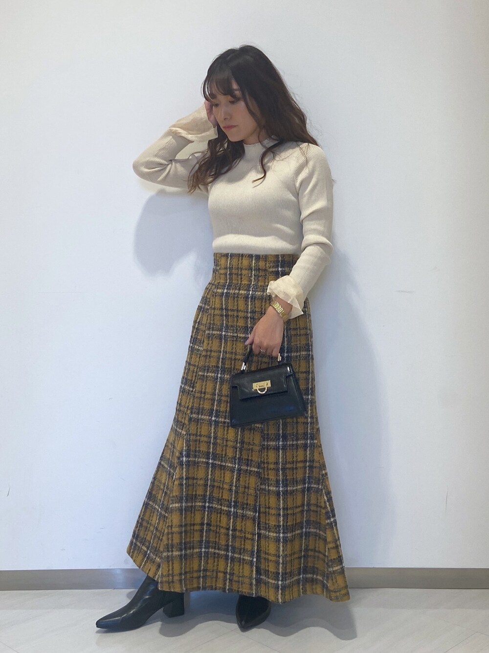 ホワイト系のニット/セーター、イエロー系のスカート、ブラック系のショルダーバッグを着用したレディースの秋コーディネートの2枚目の写真