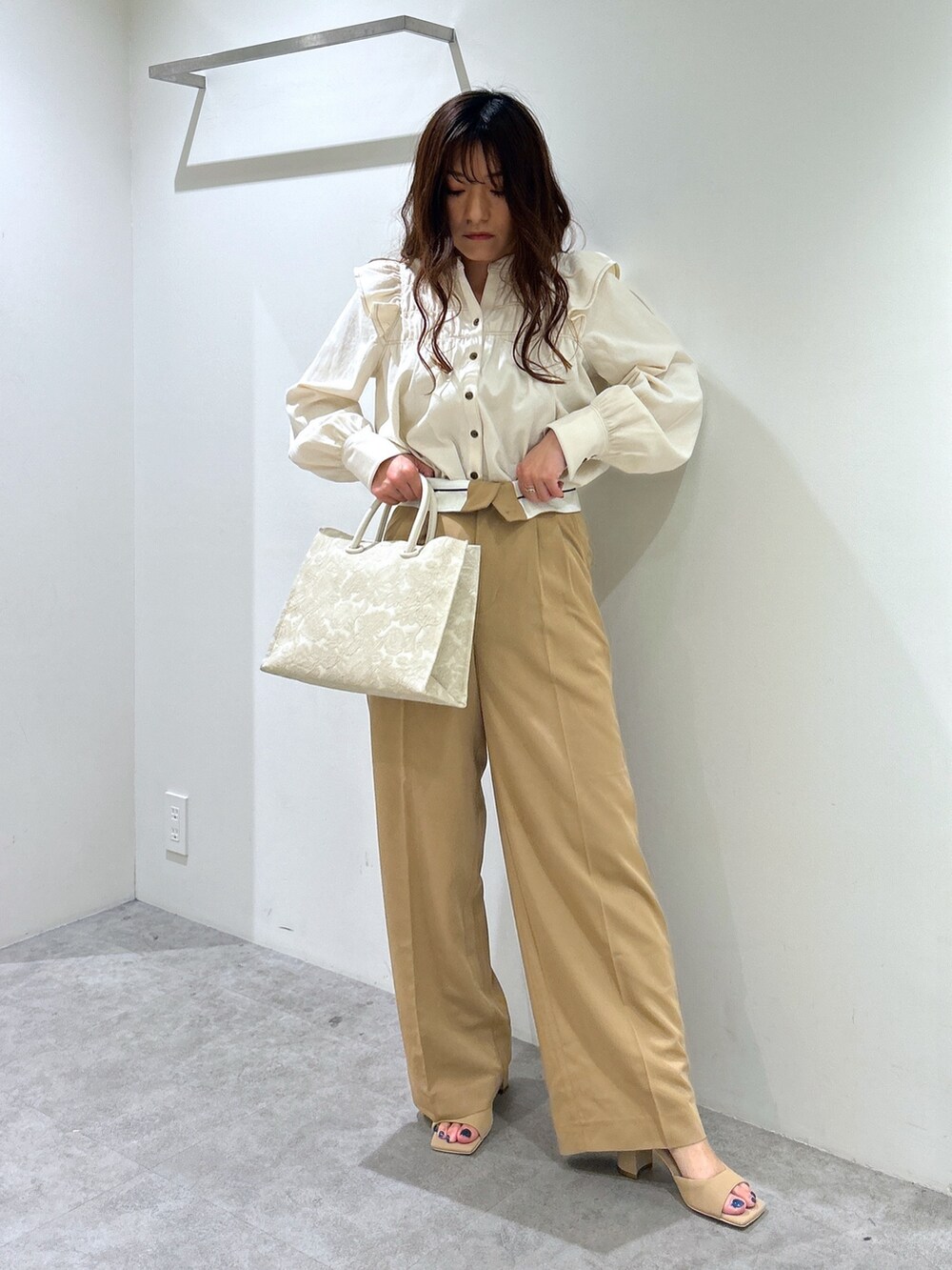 ホワイト系のシャツ/ブラウス、ホワイト系のトートバッグ、ベージュ系のスラックスを着用したレディースの春コーディネートの4枚目の写真