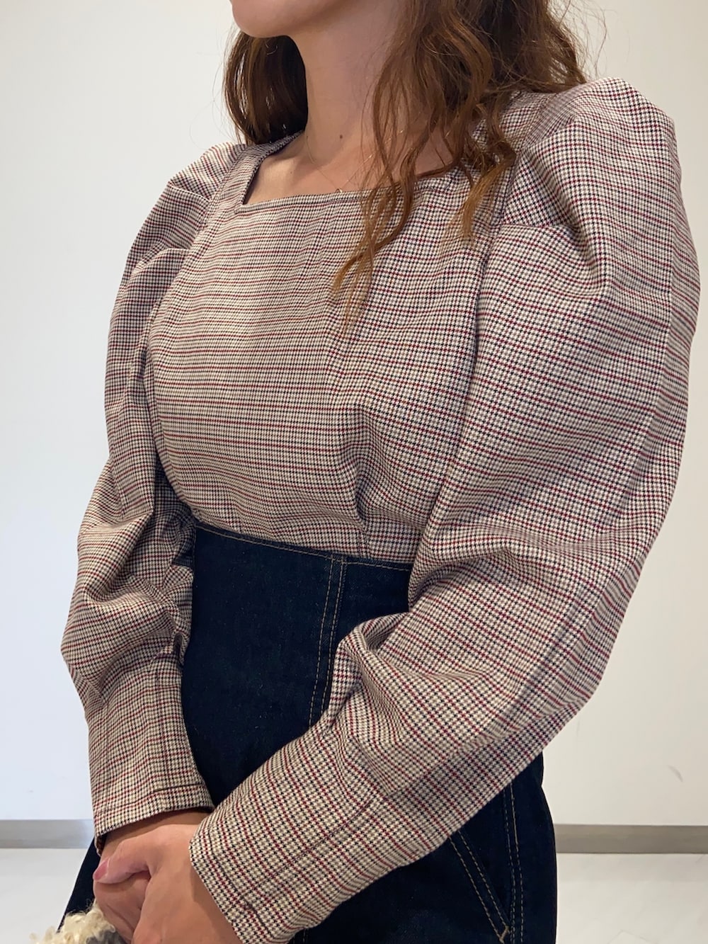 レッド系のシャツ/ブラウス、ブラック系のショルダーバッグ、ブルー系のデニムパンツを着用したレディースの秋コーディネートの4枚目の写真