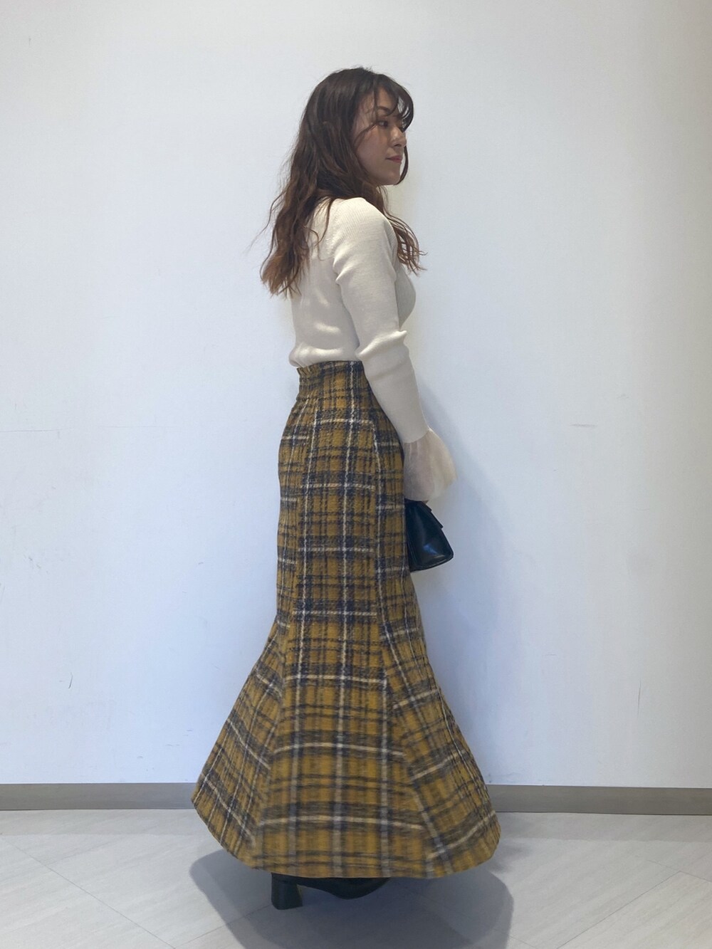 ホワイト系のニット/セーター、イエロー系のスカート、ブラック系のショルダーバッグを着用したレディースの秋コーディネートの4枚目の写真
