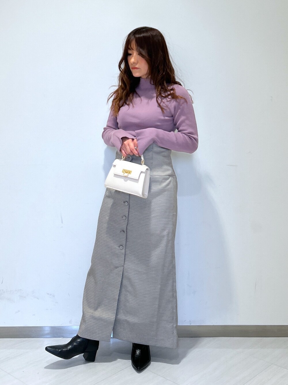 ホワイト系のショルダーバッグ、パープル系のニット/セーター、ベージュ系のスカートを着用したレディースの冬コーディネートの3枚目の写真