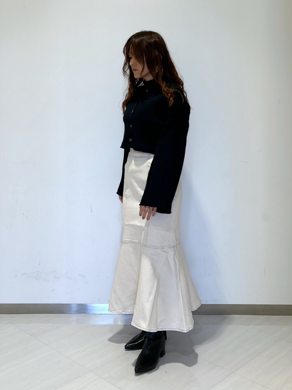 ホワイト系のデニムスカート、ブラック系のブーツ、ブラック系のカーディガン/ボレロを着用したレディースの冬コーディネートの4枚目の写真