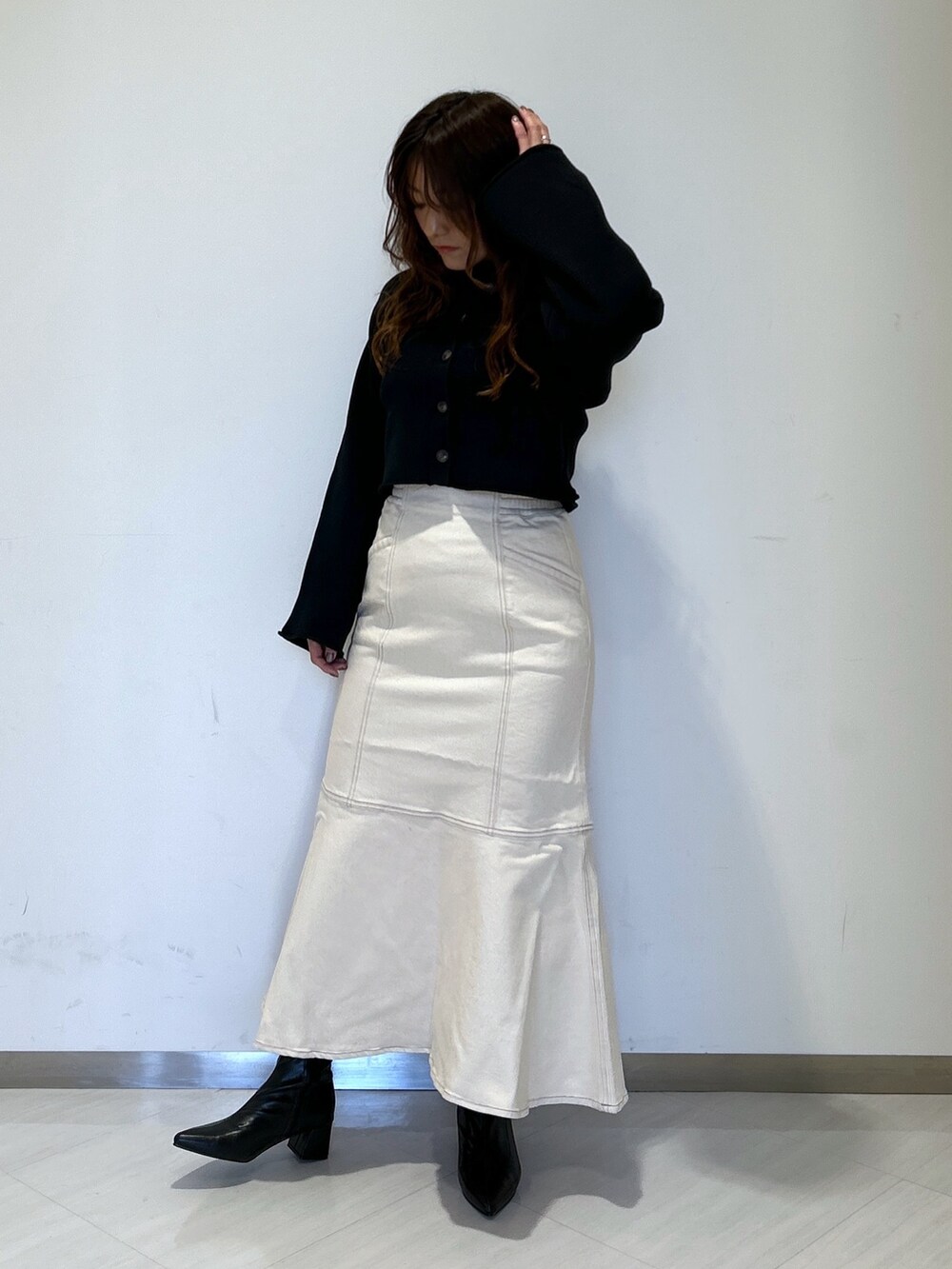 ホワイト系のデニムスカート、ブラック系のブーツ、ブラック系のカーディガン/ボレロを着用したレディースの冬コーディネートの5枚目の写真