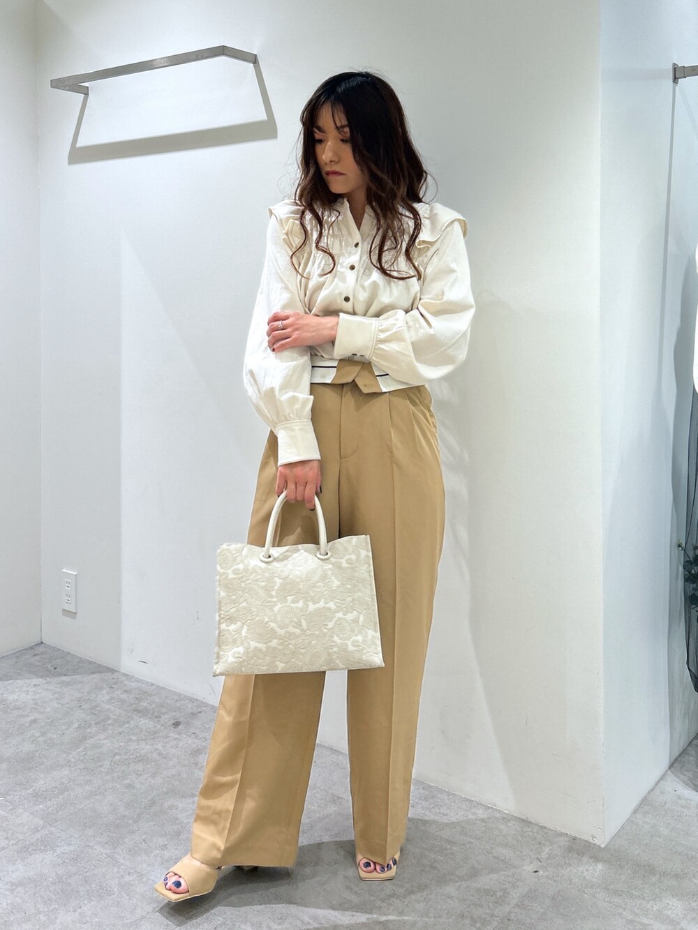 ホワイト系のシャツ/ブラウス、ホワイト系のトートバッグ、ベージュ系のスラックスを着用したレディースの春コーディネートの5枚目の写真