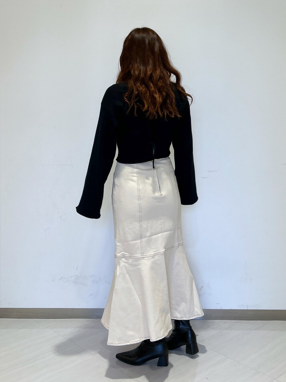 ホワイト系のデニムスカート、ブラック系のブーツ、ブラック系のカーディガン/ボレロを着用したレディースの冬コーディネートの2枚目の写真