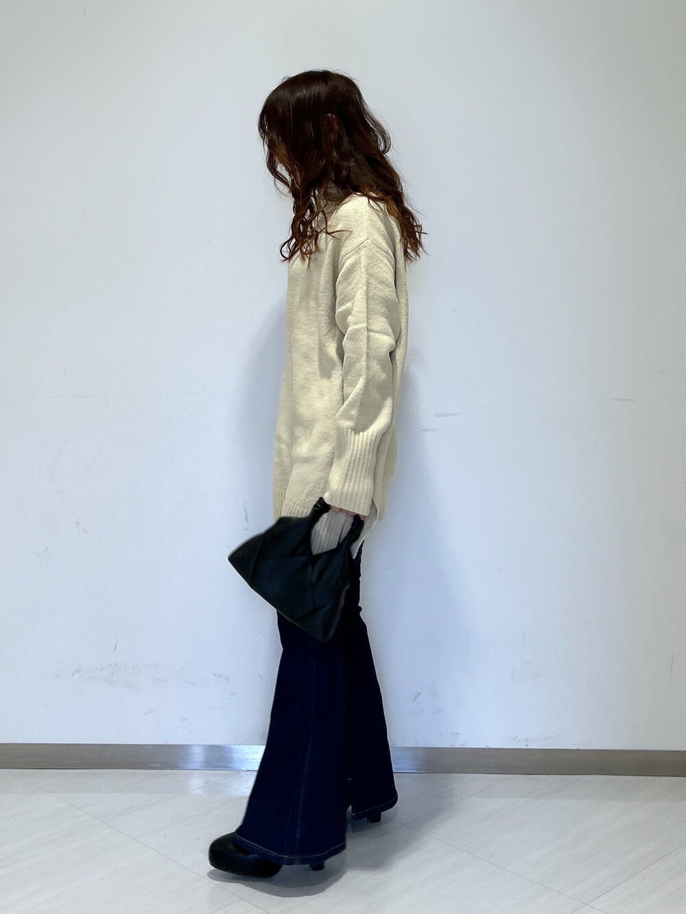 ホワイト系のニット/セーター、ブラック系のショルダーバッグ、ブルー系のデニムパンツを着用したレディースの冬コーディネートの3枚目の写真