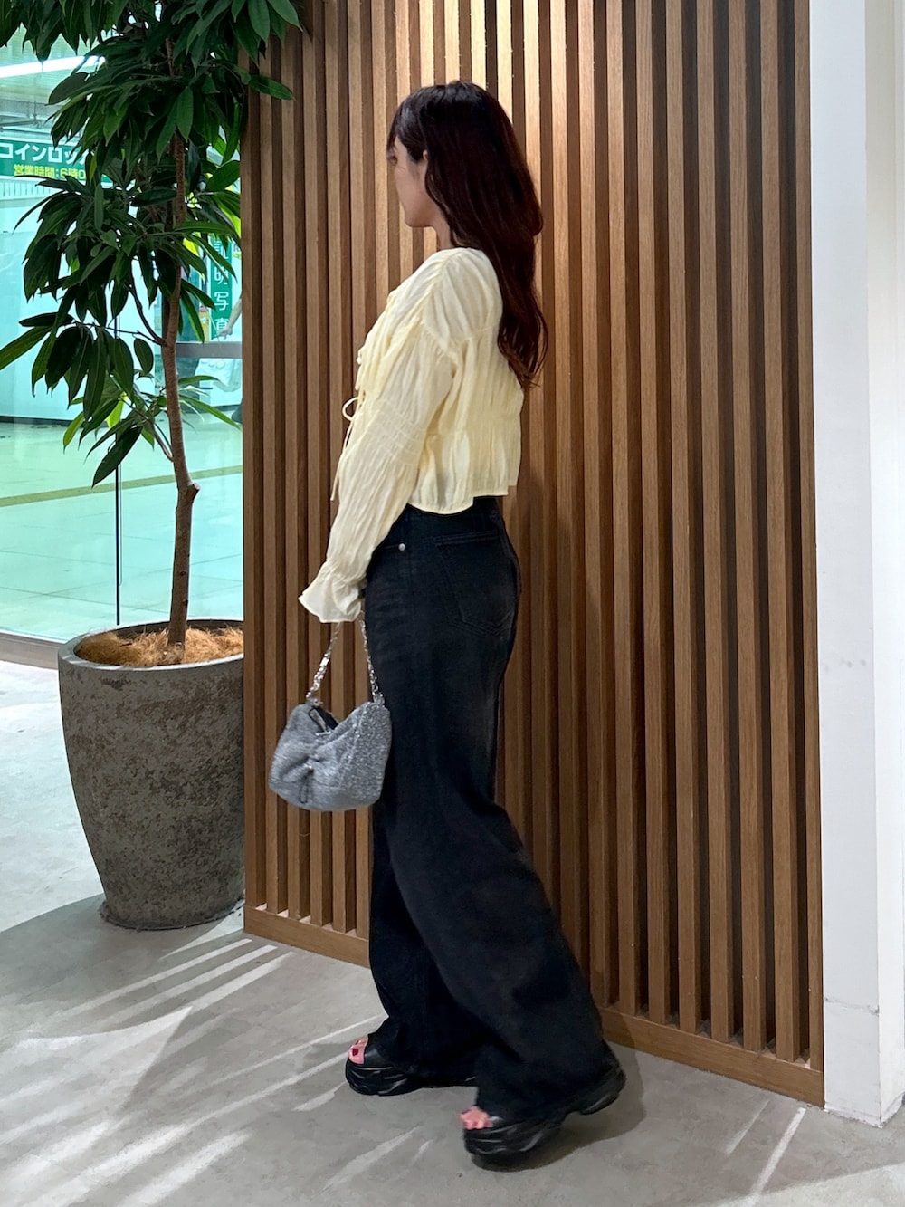 イエロー系のカーディガン/ボレロ、ホワイト系のキャミソール、ブラック系のデニムパンツを着用したレディースの夏コーディネートの3枚目の写真