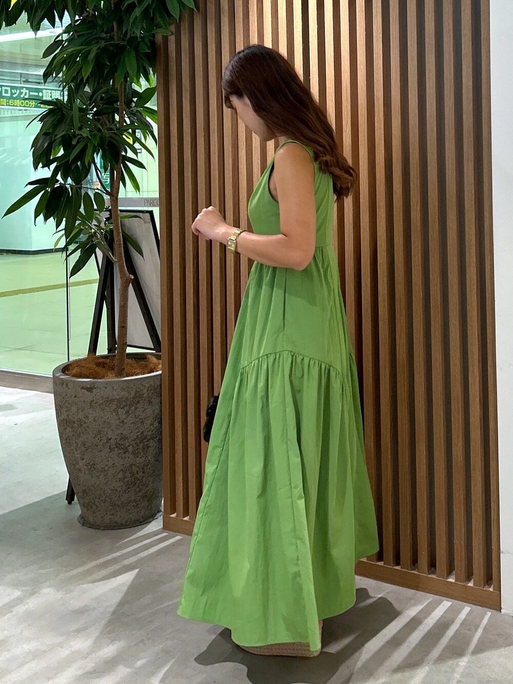 グリーン系のワンピース、ブラック系のハンドバッグ、ホワイト系のサンダルを着用したレディースの夏コーディネートの3枚目の写真