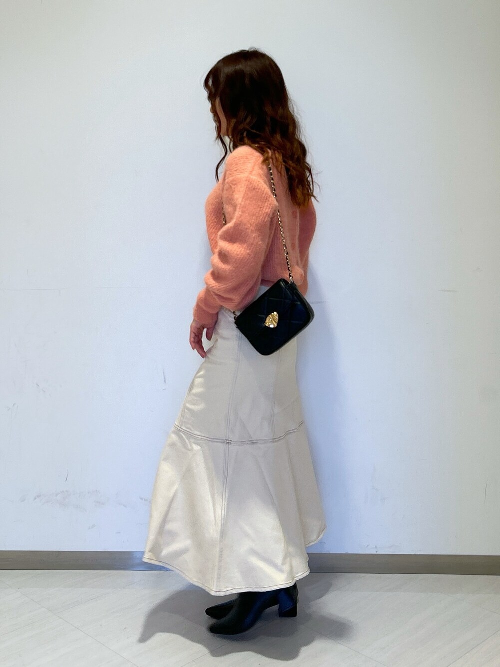 ピンク系のニット/セーター、ブラック系のショルダーバッグ、ホワイト系のデニムスカートを着用したレディースの冬コーディネートの4枚目の写真