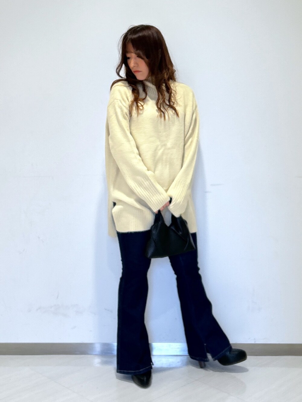 ホワイト系のニット/セーター、ブラック系のショルダーバッグ、ブルー系のデニムパンツを着用したレディースの冬コーディネートの4枚目の写真