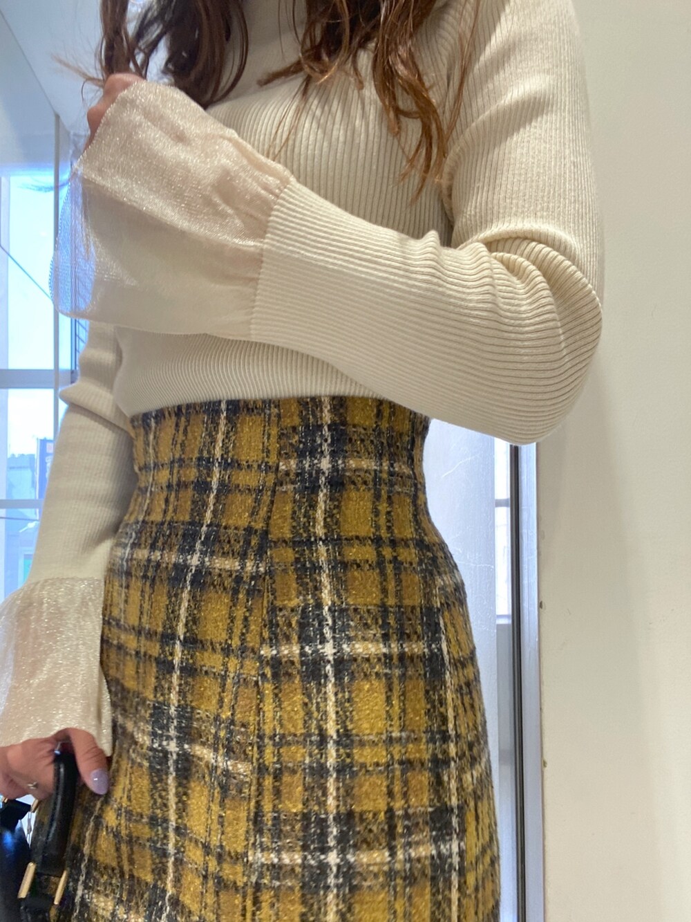 ホワイト系のニット/セーター、イエロー系のスカート、ブラック系のショルダーバッグを着用したレディースの秋コーディネートの6枚目の写真