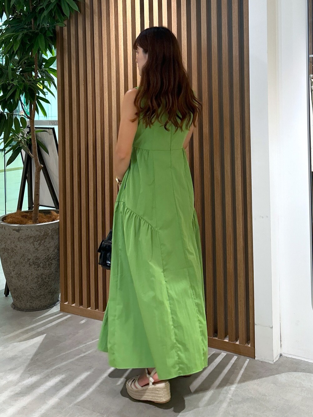 グリーン系のワンピース、ブラック系のハンドバッグ、ホワイト系のサンダルを着用したレディースの夏コーディネートの5枚目の写真