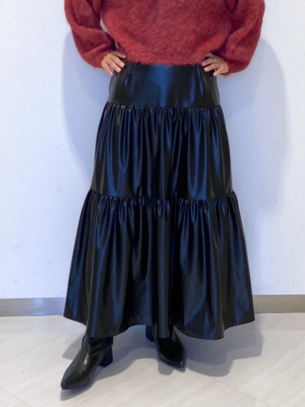 レッド系のニット/セーター、ブラック系のスカート、ブラック系のブーツを着用したレディースの秋コーディネートの4枚目の写真