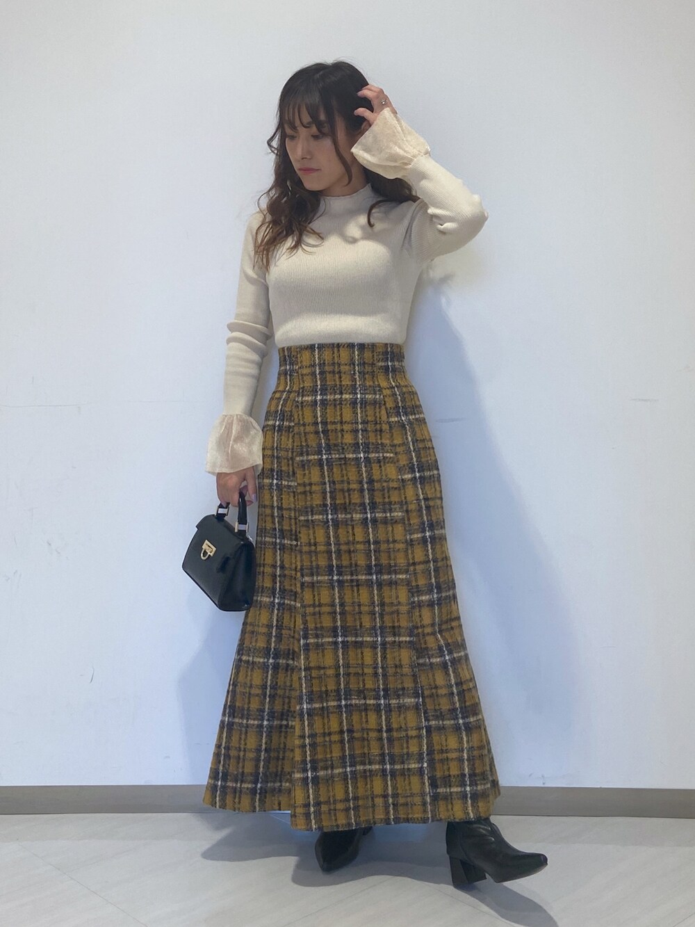 ホワイト系のニット/セーター、イエロー系のスカート、ブラック系のショルダーバッグを着用したレディースの秋コーディネートの3枚目の写真