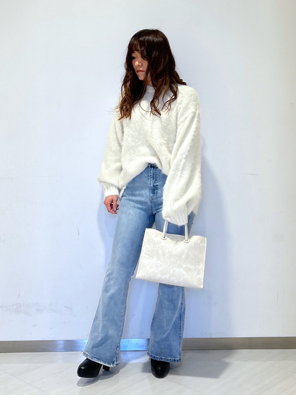 グリーン系のチェスターコート、ホワイト系のトートバッグ、ブルー系のデニムパンツを着用したレディースの冬コーディネートの4枚目の写真