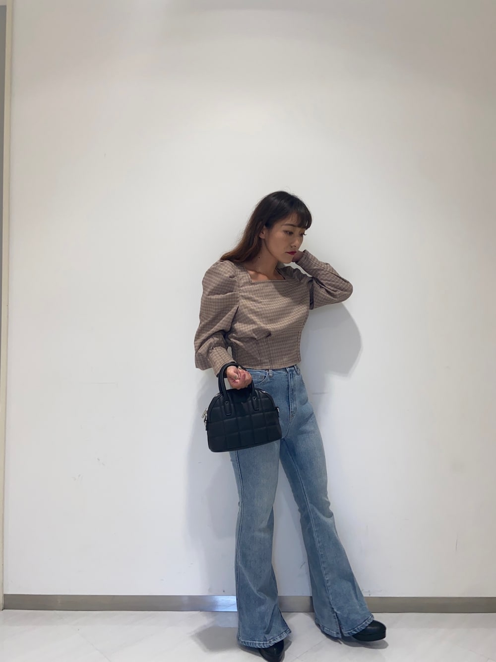 レッド系のシャツ/ブラウス、ブラック系のショルダーバッグ、ブルー系のデニムパンツを着用したレディースの秋コーディネートの2枚目の写真