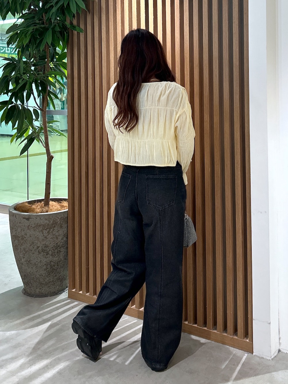 イエロー系のカーディガン/ボレロ、ホワイト系のキャミソール、ブラック系のデニムパンツを着用したレディースの夏コーディネートの2枚目の写真