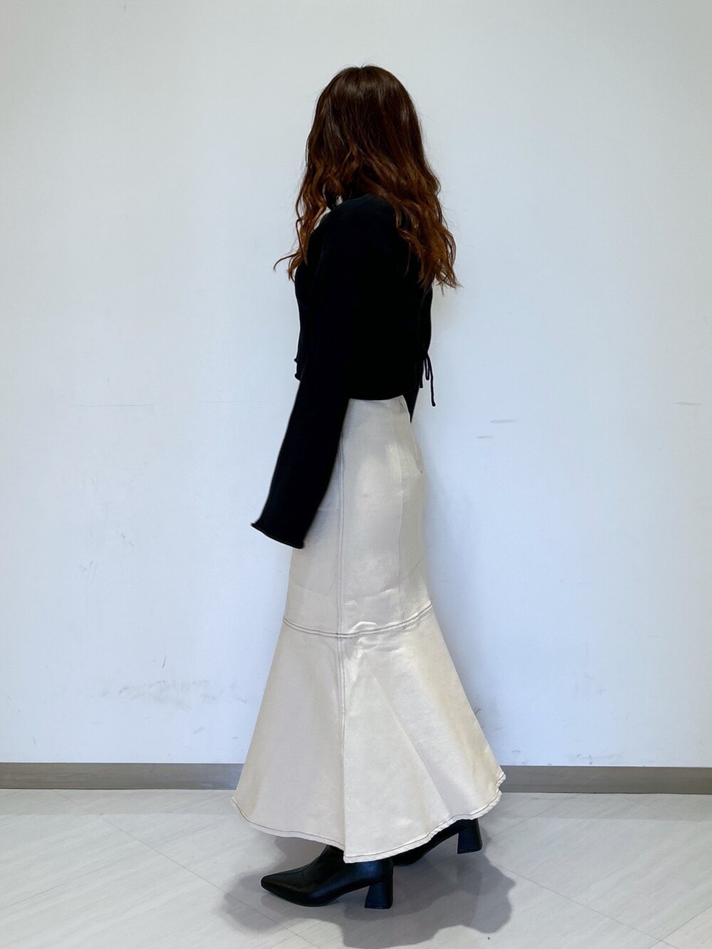 ホワイト系のデニムスカート、ブラック系のブーツ、ブラック系のカーディガン/ボレロを着用したレディースの冬コーディネートの3枚目の写真