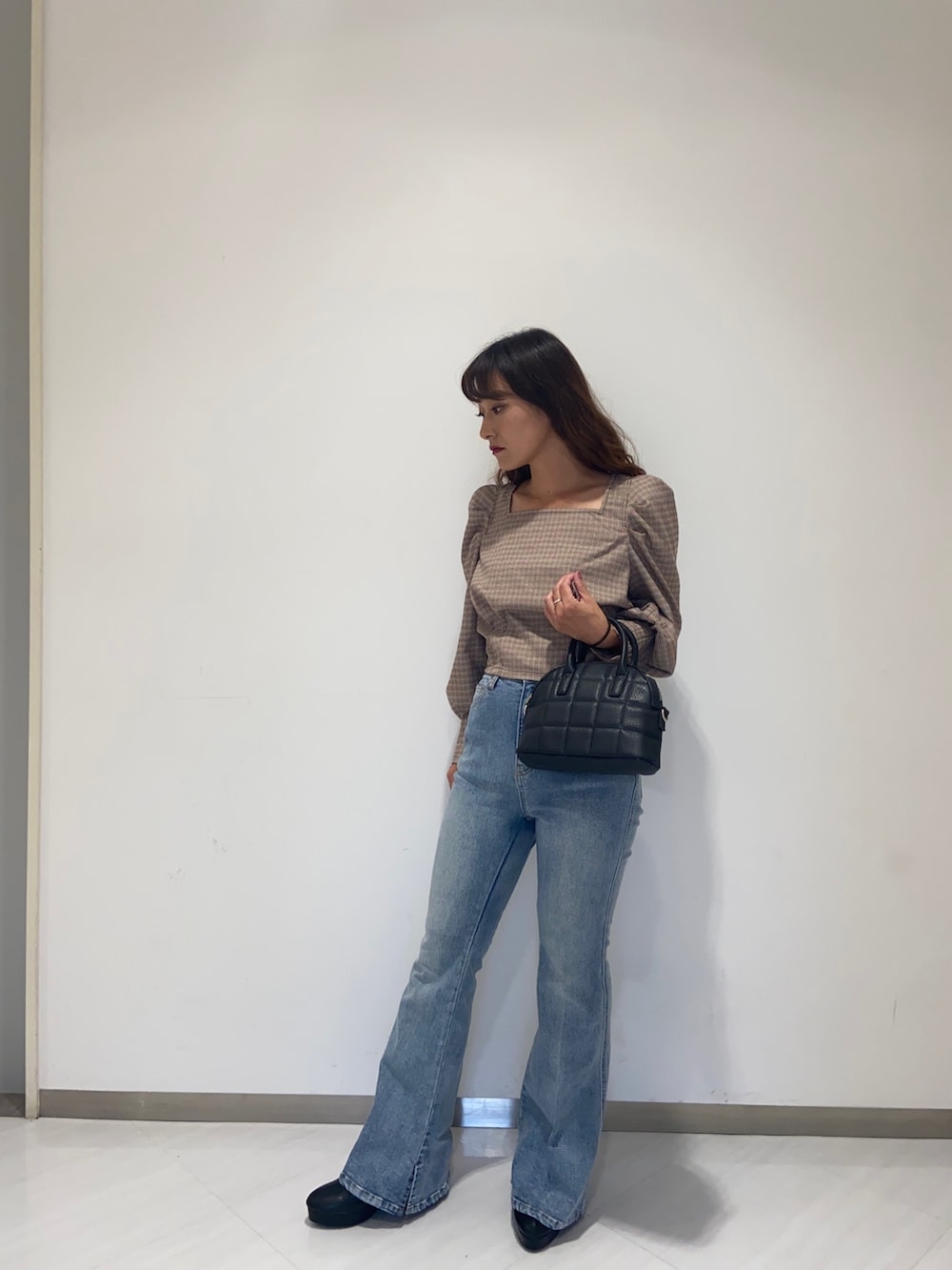 レッド系のシャツ/ブラウス、ブラック系のショルダーバッグ、ブルー系のデニムパンツを着用したレディースの秋コーディネートの3枚目の写真