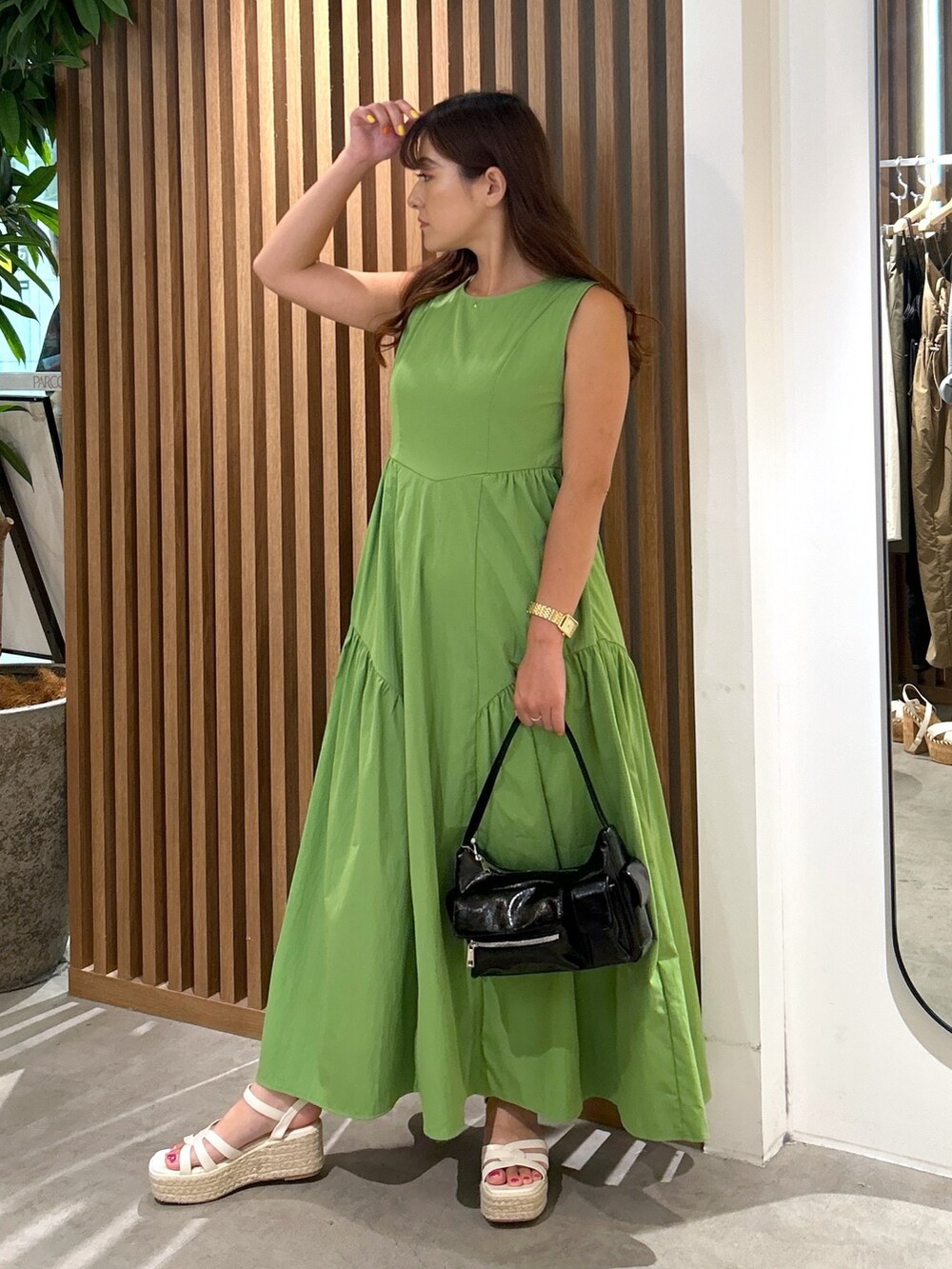 グリーン系のワンピース、ブラック系のハンドバッグ、ホワイト系のサンダルを着用したレディースの夏コーディネートの6枚目の写真