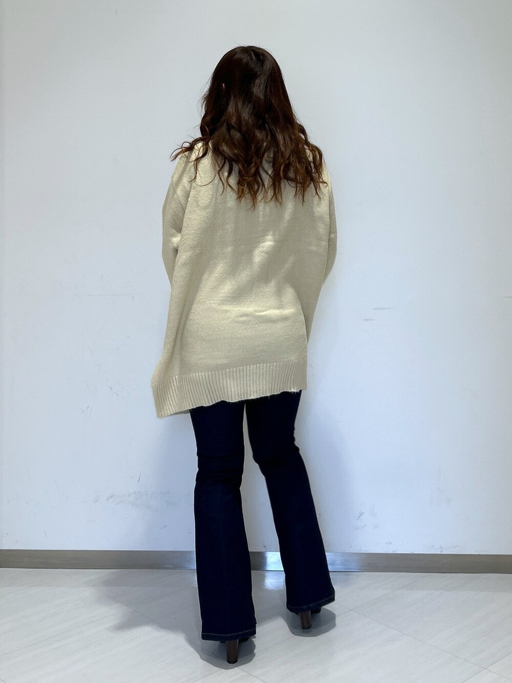 ホワイト系のニット/セーター、ブラック系のショルダーバッグ、ブルー系のデニムパンツを着用したレディースの冬コーディネートの2枚目の写真